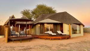 a house with a thatched roof in the desert at Kalahari Red Dunes Lodge in Kalkrand