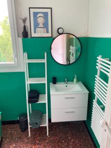 a green bathroom with a sink and a mirror at Studio Cosy, Lumineux et Bien situé. in Lorient