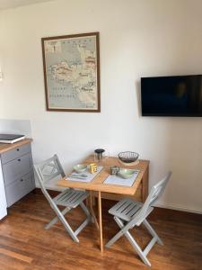 a wooden table with two chairs and a map on the wall at Studio Cosy, Lumineux et Bien situé. in Lorient