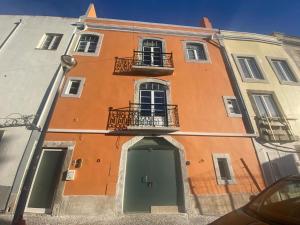an orange building with a green door and windows at Setúbal Downtown Blue in Setúbal