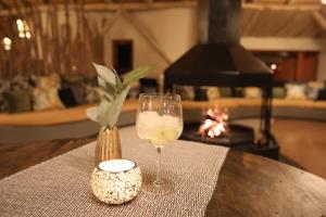 a glass of wine and a vase on a table at Kalahari Red Dunes Lodge in Kalkrand
