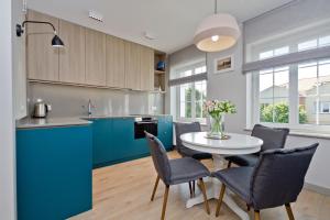 cocina con armarios azules, mesa y sillas en Apartament Wejhera, en Puck