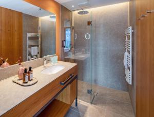 a bathroom with a sink and a glass shower at Falkensteiner Family Hotel Montafon - The Leading Hotels of the World in Schruns-Tschagguns