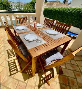 drewniany stół z płytami i kieliszkami do wina na patio w obiekcie Villa Amendoeiras 52 w Albufeirze