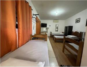 a room with two beds and a living room at Pousada Anhanguera in Ribeirão Preto