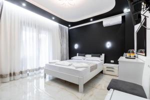 a bedroom with a white bed and a black wall at Apart-Hotel President in Ulcinj