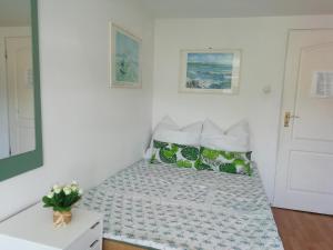 a bed in a room with a white wall at Pokoje przy fontannie in Karwia