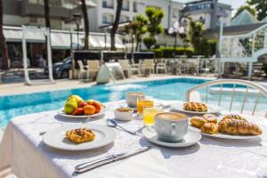 a table with plates of food on it next to a pool at Royal Boutique Hotel NUOVA GESTIONE in Riccione