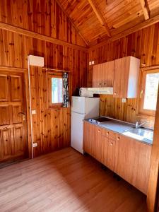 a kitchen with wooden walls and a refrigerator and a sink at Camping TurisMar in Tossa de Mar