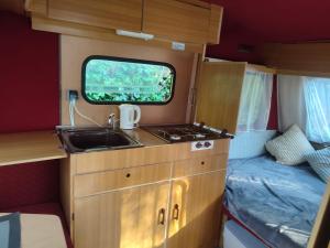 a kitchen in an rv with a sink and a bed at Przyczepa Kempingowa Niewiadów nad morzem Chłapowo in Władysławowo