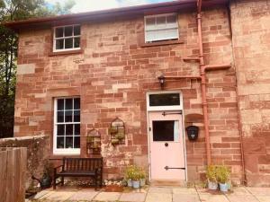 uma casa de tijolos com uma porta branca e um banco em Stylish country home near East Linton and Edinburgh em Whittingehame