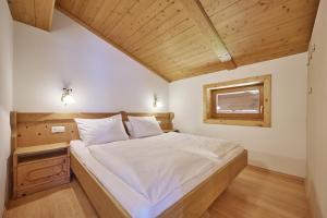 a bedroom with a large bed with a wooden ceiling at Landhaus Huber in Altenmarkt im Pongau