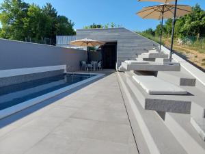 a swimming pool with benches and umbrellas on a building at MARKA I PERE in Studenci