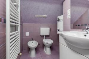 a pink bathroom with a toilet and a sink at Villa Tratea with a heated pool in Tomić Draga