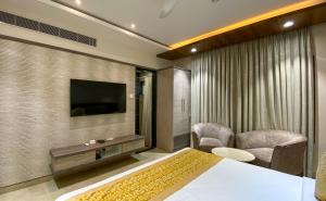 a bedroom with a bed and a television and a chair at CENTRAL A BOUTIQUE HOTEL in Belgaum