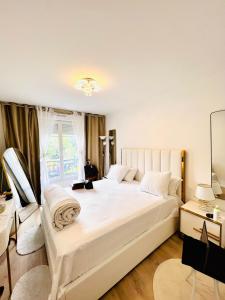 een slaapkamer met een groot wit bed en een raam bij LES RÉSIDENCES DE DJIBRIL in Le Blanc-Mesnil