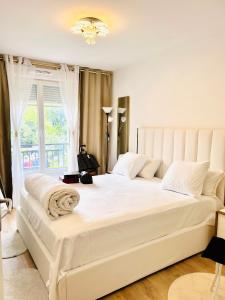 a large white bed in a room with a window at LES RÉSIDENCES DE DJIBRIL in Le Blanc-Mesnil