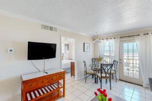 a living room with a television and a table with chairs at Beachfront Haven in Galveston
