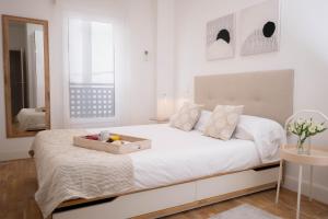een witte slaapkamer met een groot bed met een fruitmand erop bij Perfect one bedroom apartment in Madrid