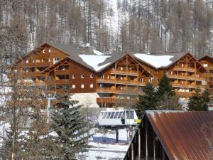 a large log cabin with snow on the roof at Terrasses de Labrau - Res piscine in Allos