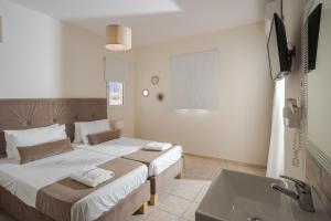 Una habitación de hotel con dos camas y un lavabo. en Despina Aparthotel by Philoxenia Hotel & SPA, en Malia