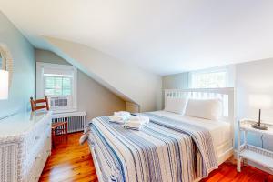 ein Schlafzimmer mit einem Bett mit einer gestreiften Decke und zwei Fenstern in der Unterkunft Herman Vincent House in Edgartown
