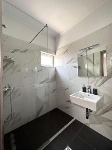 a bathroom with a sink and a glass shower at Meto Rooms in Sarandë +59 photos