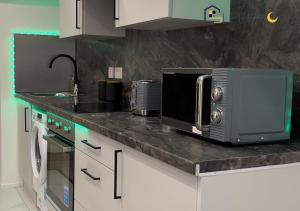 um balcão de cozinha com um micro-ondas e um lavatório em Luxury & Modern 1 BR Apartment 5Plus Guests Couples Families Business SleeepOva Short Lets & Serviced Accommodation em Londres