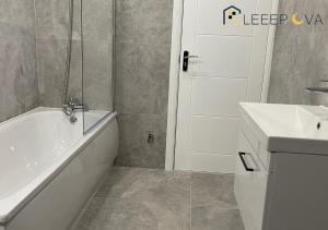 y baño con bañera blanca y lavamanos. en Luxury & Modern 1 BR Apartment 5Plus Guests Couples Families Business SleeepOva Short Lets & Serviced Accommodation en Londres