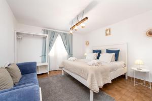 um quarto com uma cama grande e um sofá azul em Vila Maria Apartments by Host-Point em Costa da Caparica