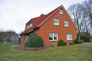 a red brick house with a red roof at Ferienwohnung Bohlen 65265 in Moormerland