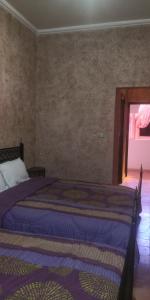 1 dormitorio con cama con sábanas azules y ventana en Will Center Assounfou, en Tiznit