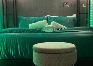 - un lit avec une couette bleue et un tabouret dans l'établissement Luxury & Spacious 2 Bedroom Flat Families Business Relocation SleeepOva Short Lets & Serviced Accommodation, à Londres