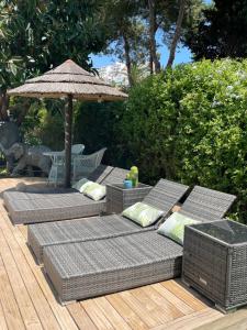three wicker chairs and an umbrella on a deck at Casa Flora - Mijas Costa - Andalusië in Mijas