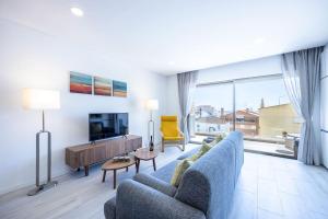 a living room with a blue couch and a tv at The Hub central apartment Burgau in Burgau
