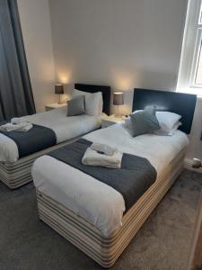 Dos camas en una habitación de hotel con toallas. en The Sanderling en Morecambe