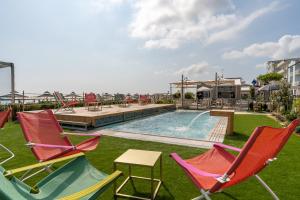 um grupo de cadeiras e uma piscina com uma mesa em Hotel Savini em Bellaria-Igea Marina