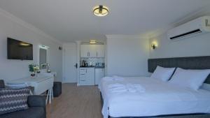 a bedroom with a large white bed and a kitchen at Miralya Suites in Fethiye
