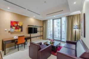 a living room with a couch and a table and a desk at Icon Delux Hotel Apartments Al Barsha - Formerly Abidos in Dubai