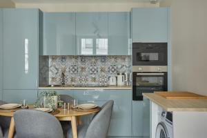 a kitchen with blue cabinets and a table with chairs at Charming apartment Center of Paris/Montorgueil ( Aboukir 78) in Paris