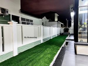 a house with a white fence and green grass at Rz Homestay in Malacca