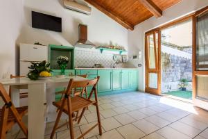 uma cozinha com armários verdes e uma mesa e cadeiras em [Sorrento Coast] Villa with garden Il Glicine em Piano di Sorrento