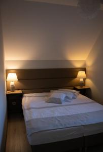 a bedroom with a large white bed with two lamps at Apartamenty nad Strumykiem in Brenna