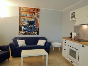 ein Wohnzimmer mit einem blauen Sofa und einer Küche in der Unterkunft Le Cottage des 3 Pignons in Noisy-sur-École