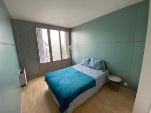 um quarto com uma cama com lençóis azuis e uma janela em Belle vue de Lognes- 15min Disney/ 5min gare / Parking gratuit em Lognes