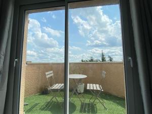a view of a patio with a table and chairs through a window at Belle vue de Lognes- 15min Disney/ 5min gare / Parking gratuit in Lognes