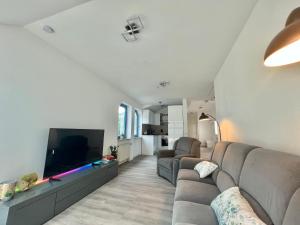 uma sala de estar com um sofá e uma televisão de ecrã plano em Premium FeWo - Blick auf Felsenkirche & Schloss - Traveller AWARD 2024 em Idar-Oberstein