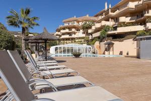 a row of lounge chairs and umbrellas next to a building at 5* Serviced Apartment Marbella in Marbella
