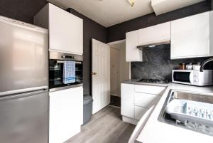 een keuken met witte kasten en roestvrijstalen apparatuur bij A home away from home - Derby in Derby