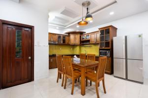 The Lovenote Home في مدينة هوشي منه: مطبخ مع طاولة وكراسي خشبية وثلاجة